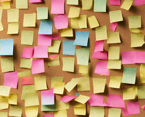 Image of a cork board full of post-it notes.